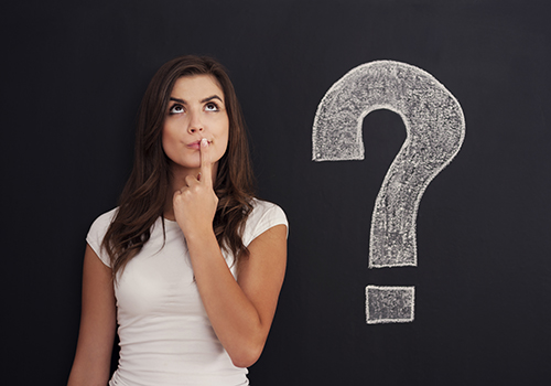 Inquisitive woman next to question mark on blackboard
